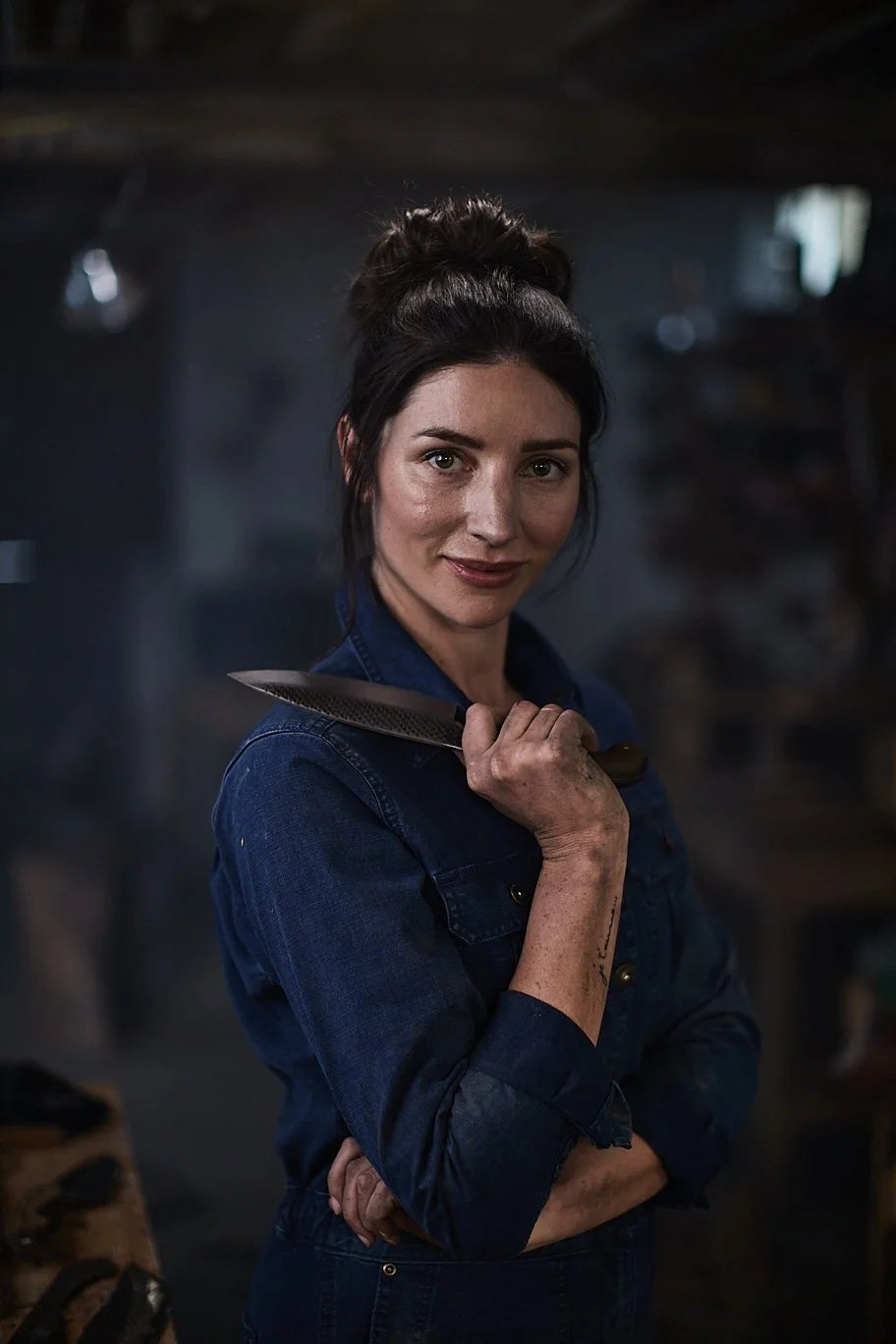 Chelsea Miller holding a hand forged knife in her Brooklyn workshop