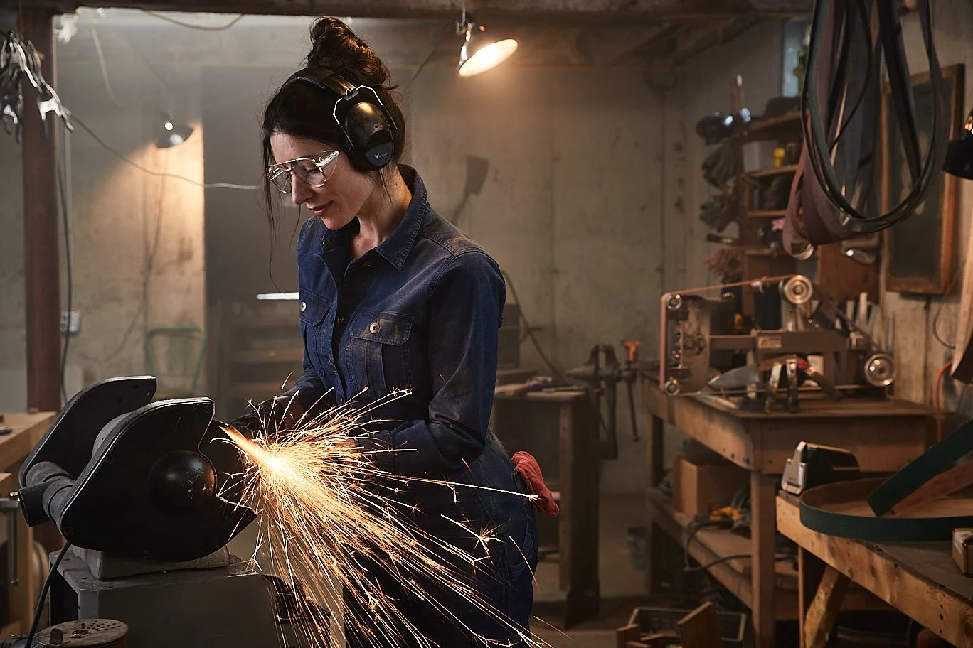 Chelsea Miller grinding a knife in her workshop, sparks flying
